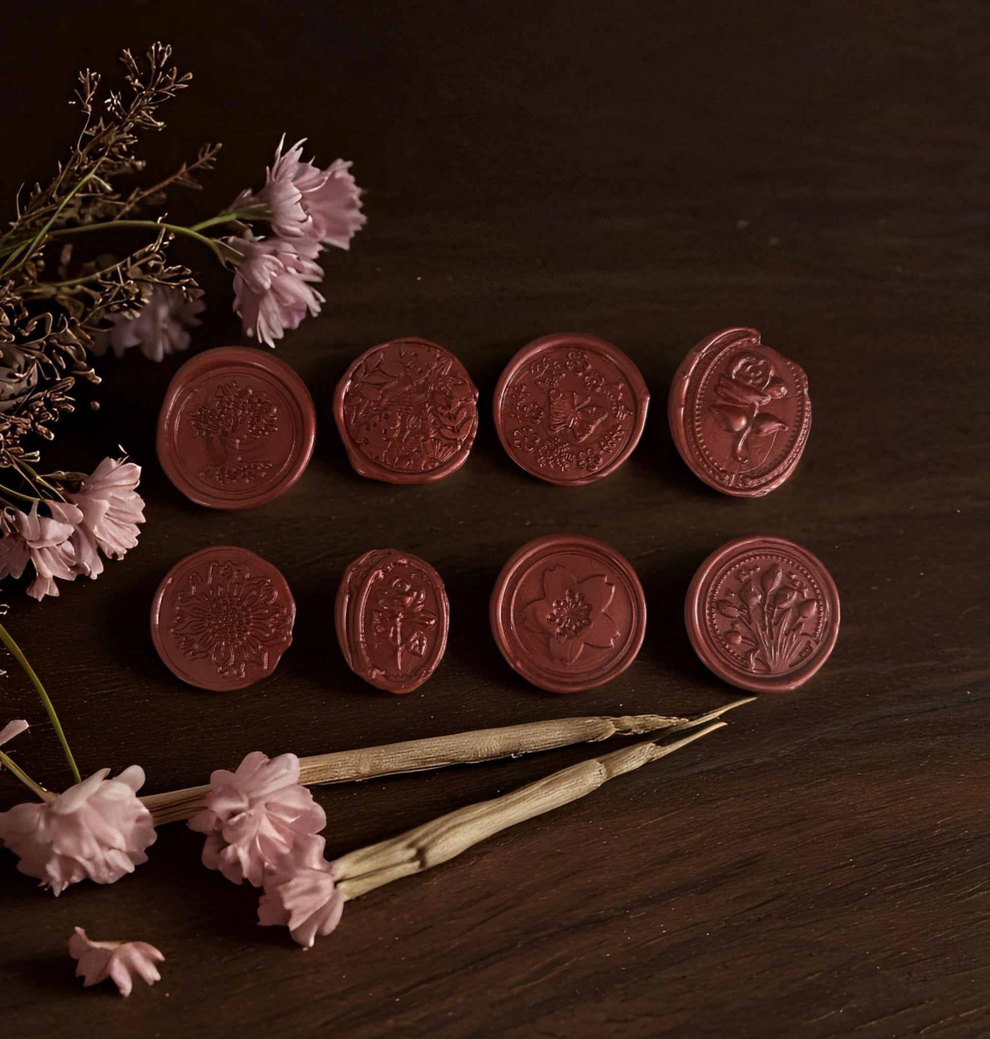 Set of red wax seals on a wooden surface with flowers