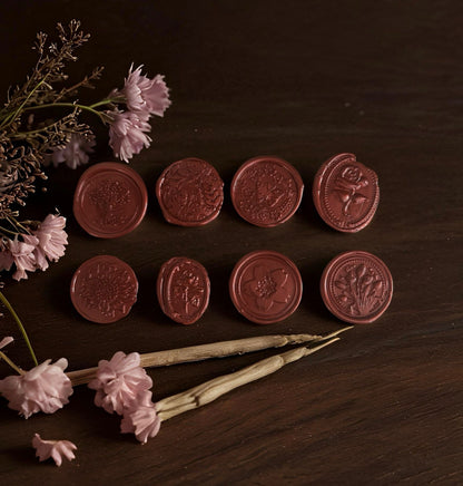 Set of red wax seals on a wooden surface with flowers