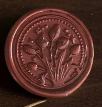 Round brown stamp with floral design on a dark background